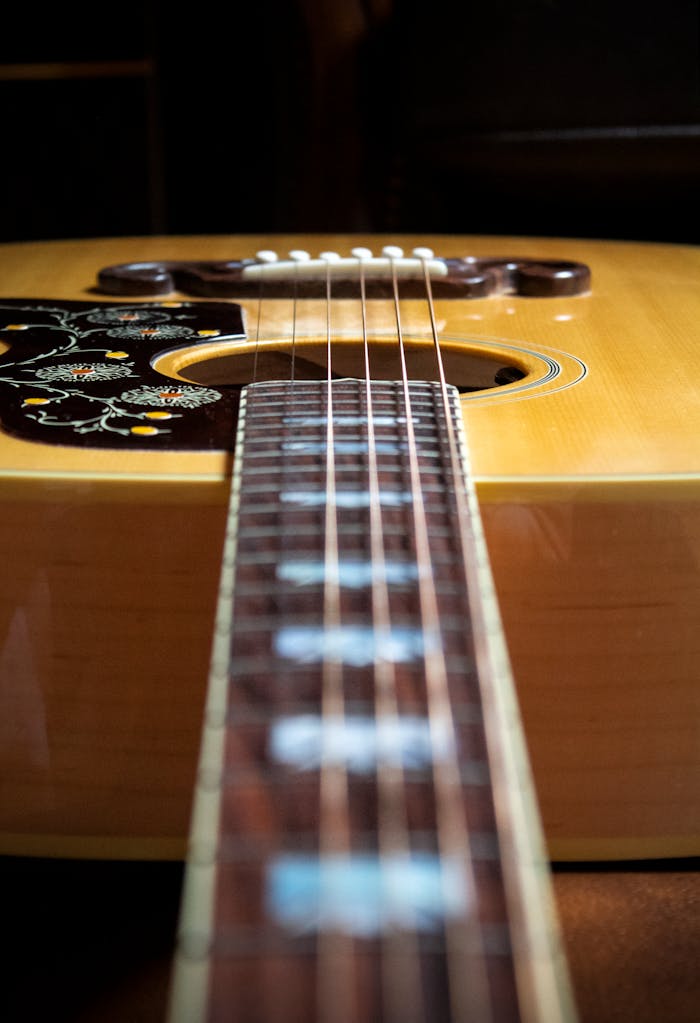 Detailed view of an acoustic guitar neck with intricate design on the body, offering a warm and artistic feel.